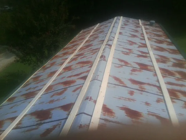 Rusted metal roof panels with new wood purlins before replacement in Warriors Mark