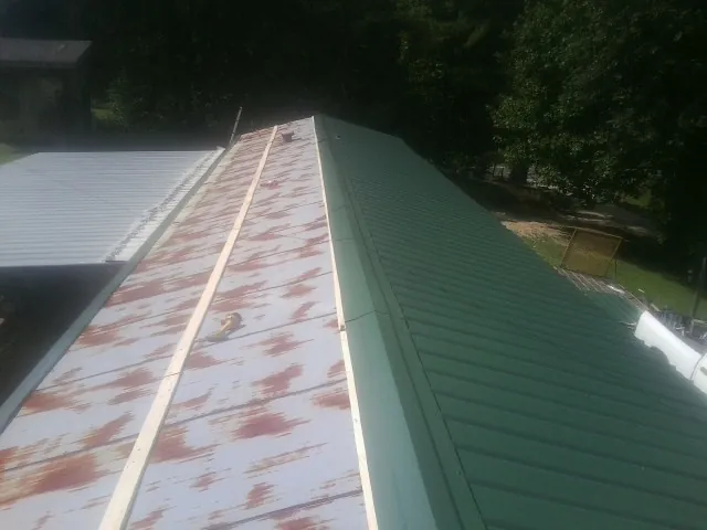 Old rusted panels beside newly installed green metal roofing — Wind Damage Roof Repair by Roofing Brothers in Warriors Mark