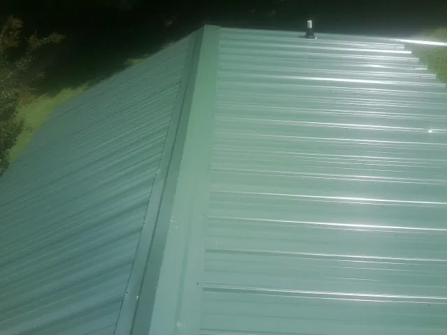 New green metal panels meeting at the ridge of a roof — Flat Roof Repair work by our crew in Warriors Mark