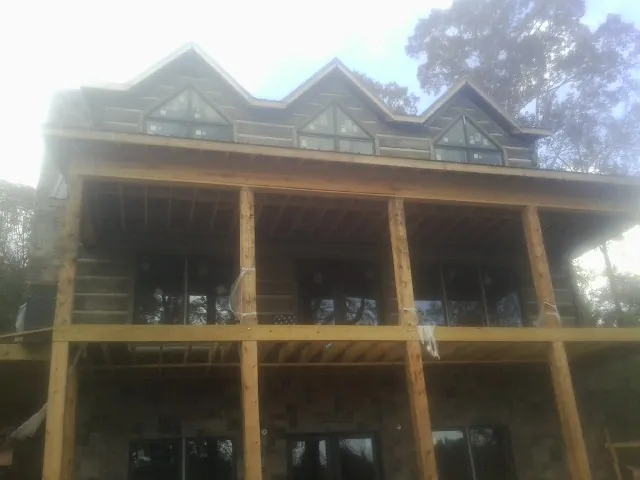 Dormers and porch framing on a large log home under construction — Roof Coating work by our crew in Warriors Mark