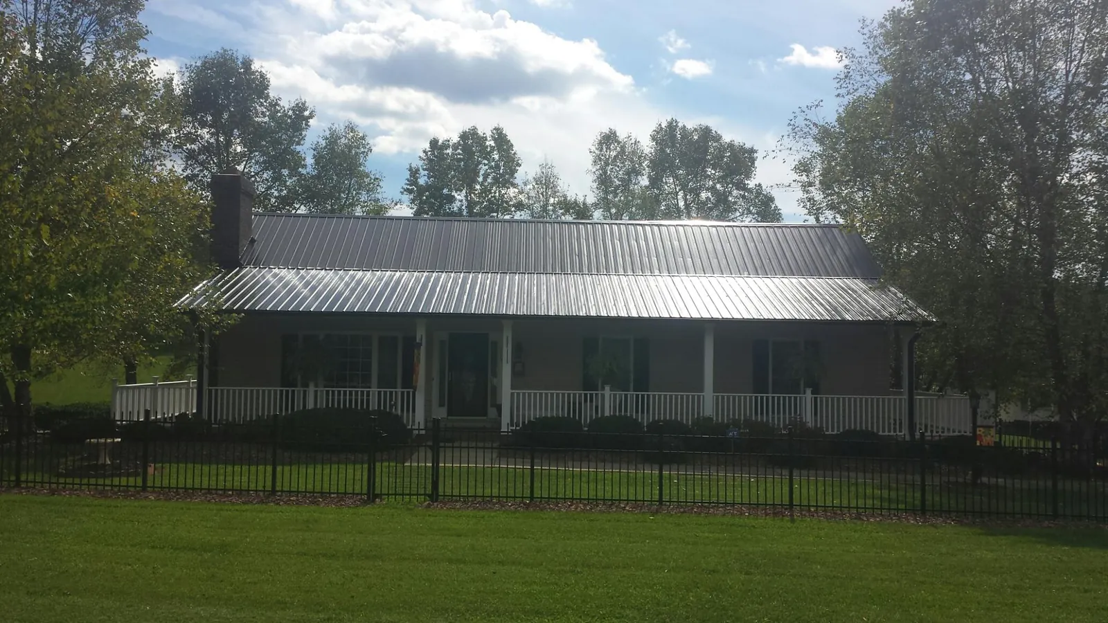 Gray metal roof on a brick ranch with a full width front porch — Gutter Guard Installation work by our crew in Warriors Mark