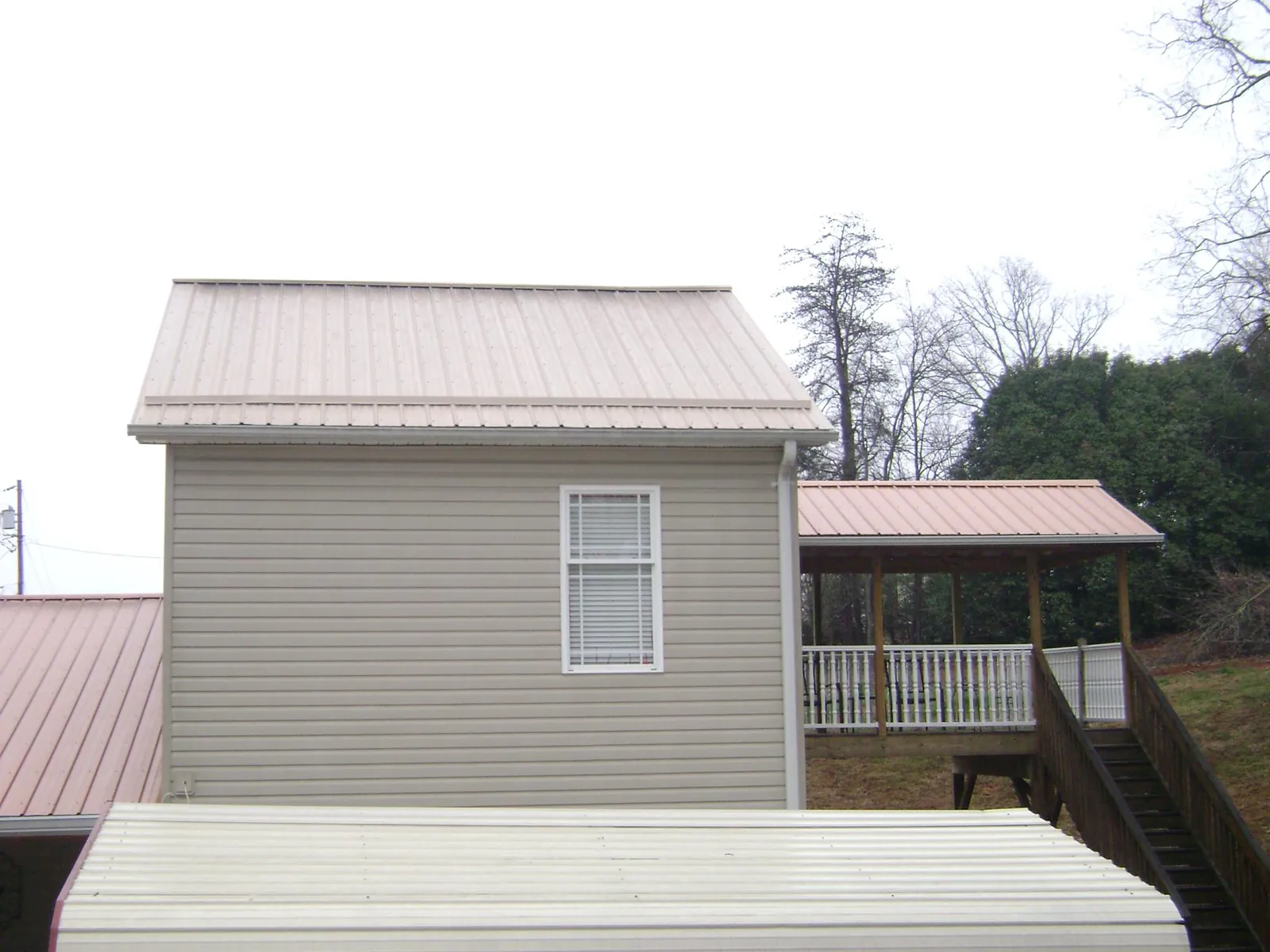 Tan metal roofs on a two story addition and attached porch, from a Roof Replacement job in Warriors Mark