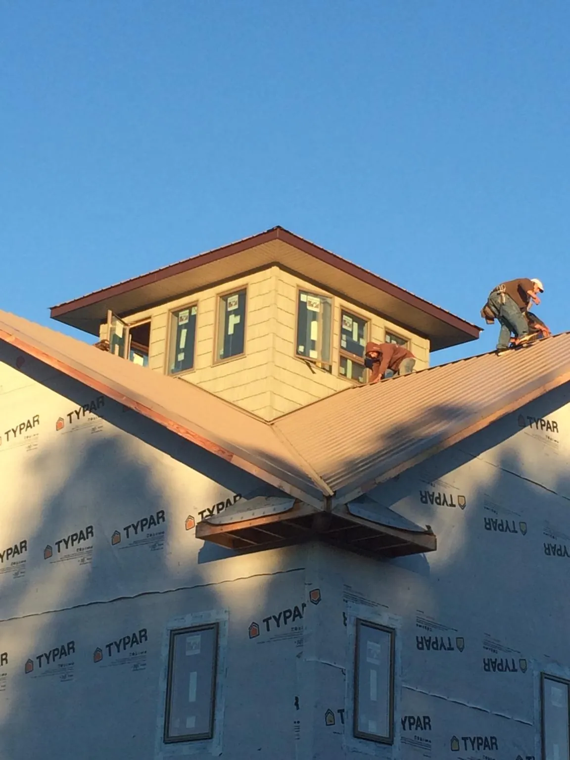 Roofers working around a rooftop cupola on a new metal roof at sunset — Roof Waterproofing in Warriors Mark by Roofing Brothers